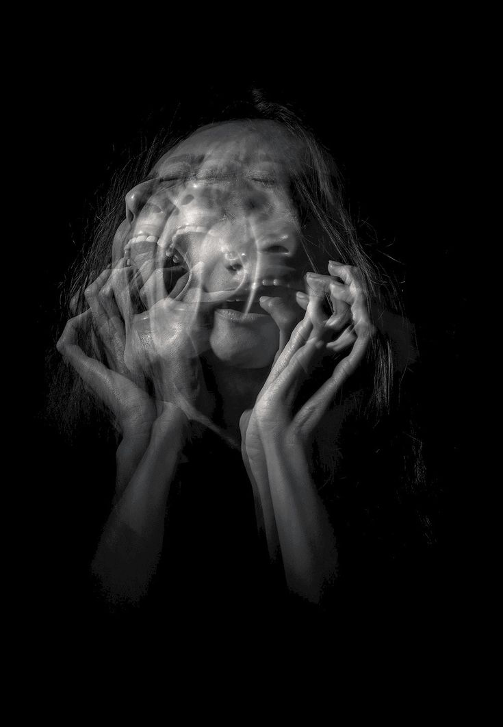 A fractured, ghostly face dissolving into darkness